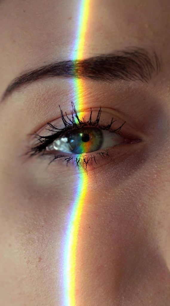 Le visage d'une femme avec un arc-en-ciel qui traverse son oeil