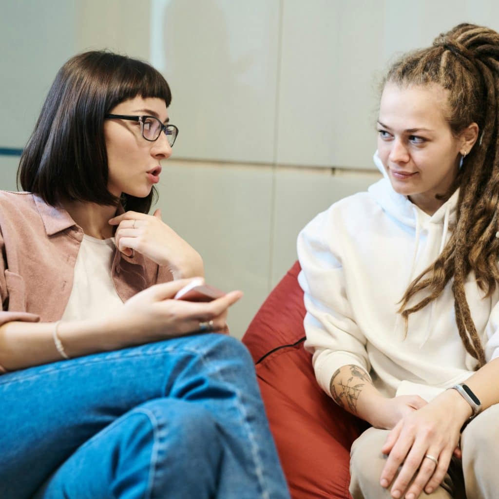 Deux femmes parlent assises sur des fauteuils rouge